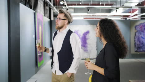 una pareja disfrutando de champán en una galería de arte.