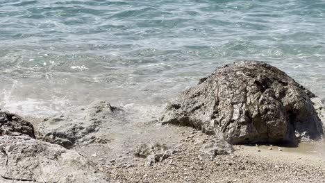 clear turquoise seawater gently washes onto a sandy, rocky beach in croatia. the calm adriatic scene highlights nature, travel, and a peaceful summer holiday atmosphere