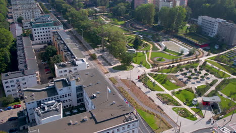 aerial forward view over urban landscape, buildings cars and public garden