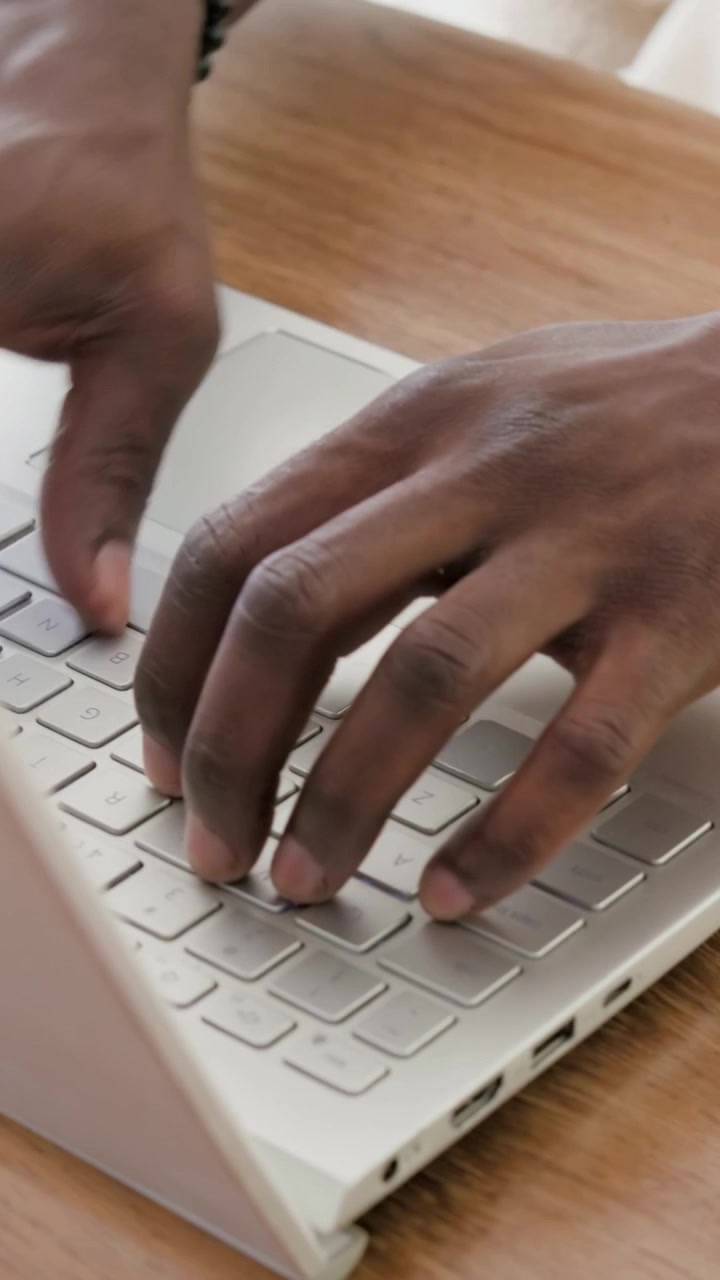 Video verticale: Prende il telefono, mani che controllano lo schermo, poi digitano alla scrivania sul laptop con un orologio.