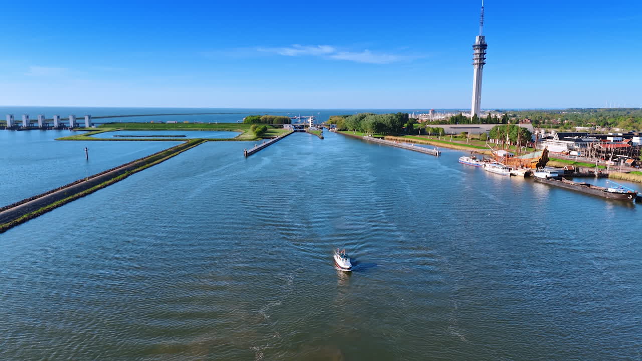 Netherlands boating waterways. A boat glides through calm waters near the coast of the Netherlands, surrounded by green landscapes and structures