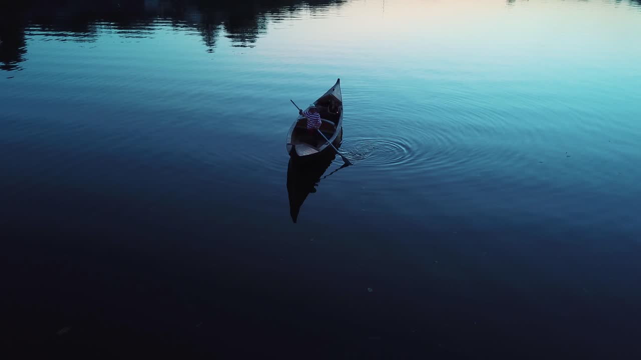 Aerial view of a young girl lying in a boat floating on a lake at night. Gondola with gondolier