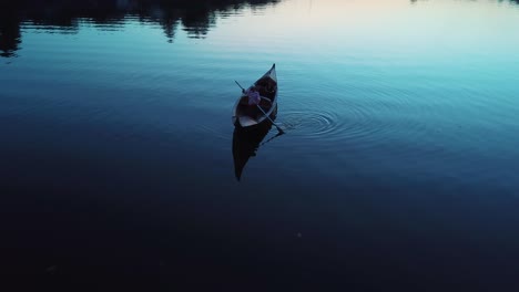 aerial view of a young girl lying in a boat floating on a lake at night. gondola with gondolier