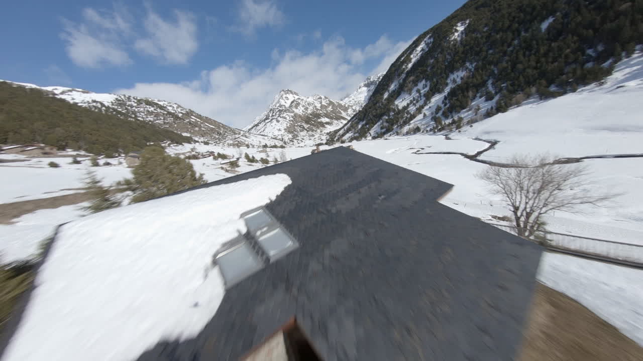 fpv aéreo sobre cabañas en el valle nevado de incles con la cordillera de los pirineos en el fondo, andorra