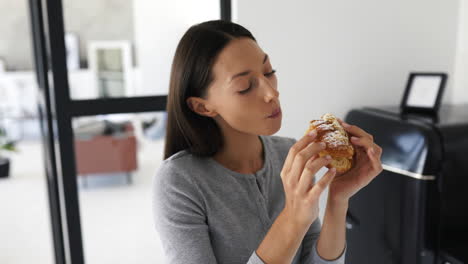 mujer comiendo un delicioso croissant en una cocina moderna