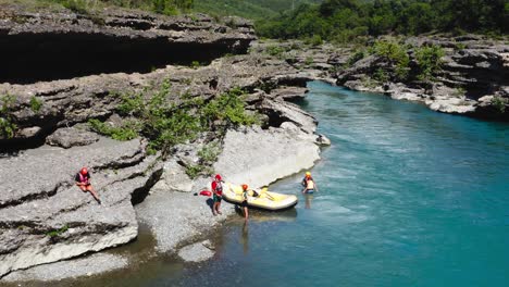 tourists disembark from inflatable boat at the vjosa river edge after rafting, in albania