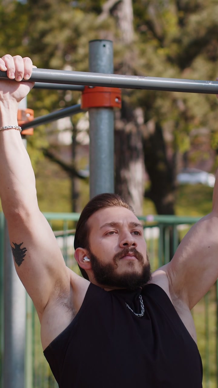 Athletic lebanese man in sportswear doing pull ups exercises on horizontal bar pumping up back