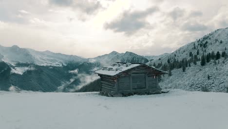 alpine hut in front of snow covered mountains with the first fresh snow of the season