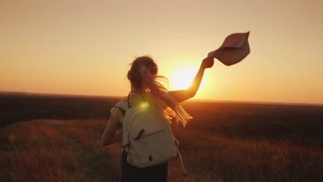 funny girl in a straw hat runs down the hill at sunset holds the hat with his hands leto and the vac