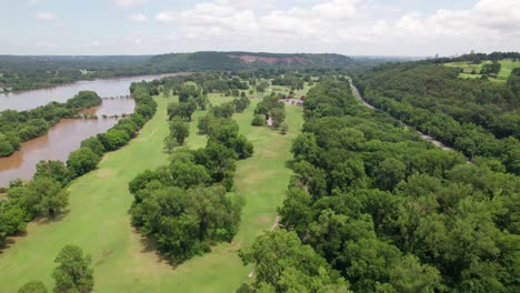 aerial footage of the rebsamen park golf course. the arkansas river is to the left and the golf course, trees, greens and sand traps are visible