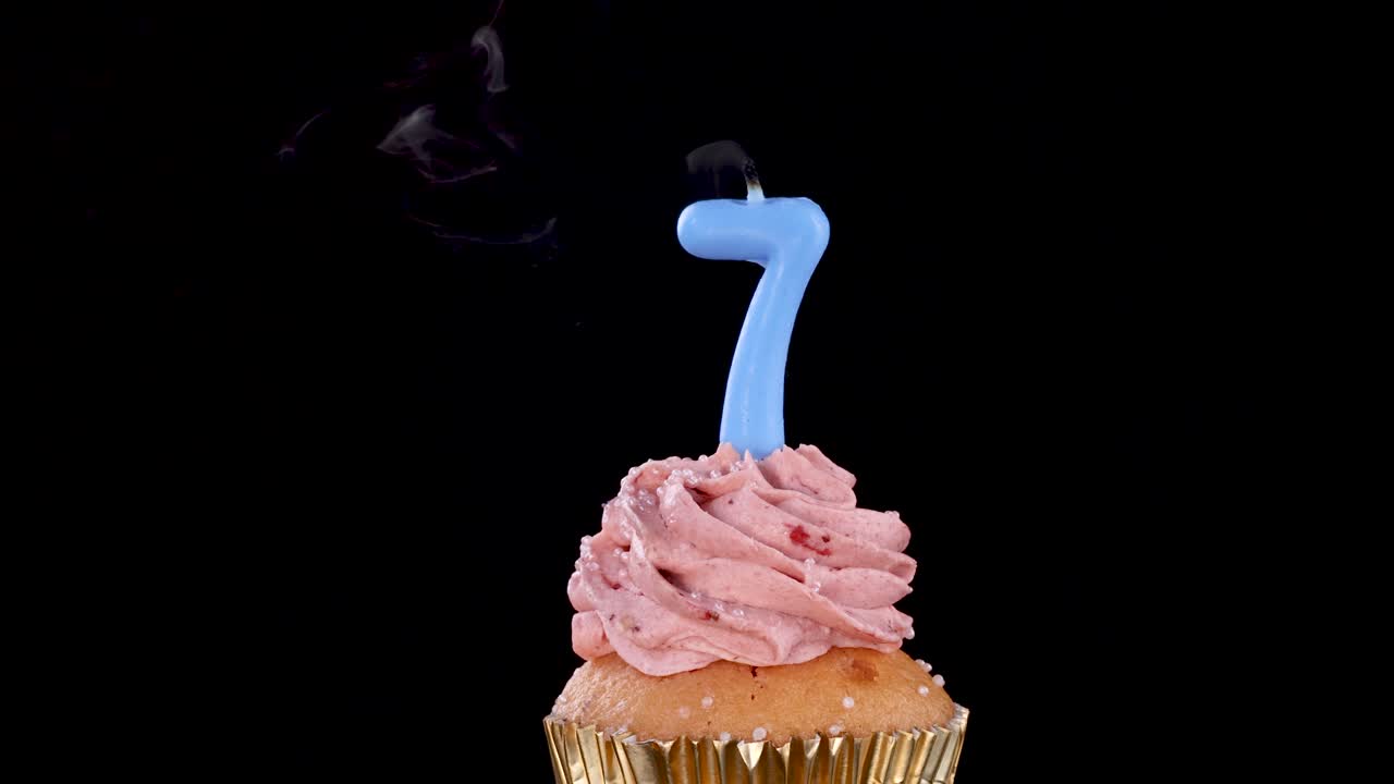 Blue number seven candle blown out on strawberry cupcake, smoke swirling under dramatic studio lighting