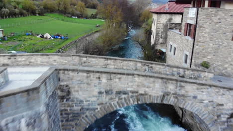 aerial footage of stone european bridge over rushing river