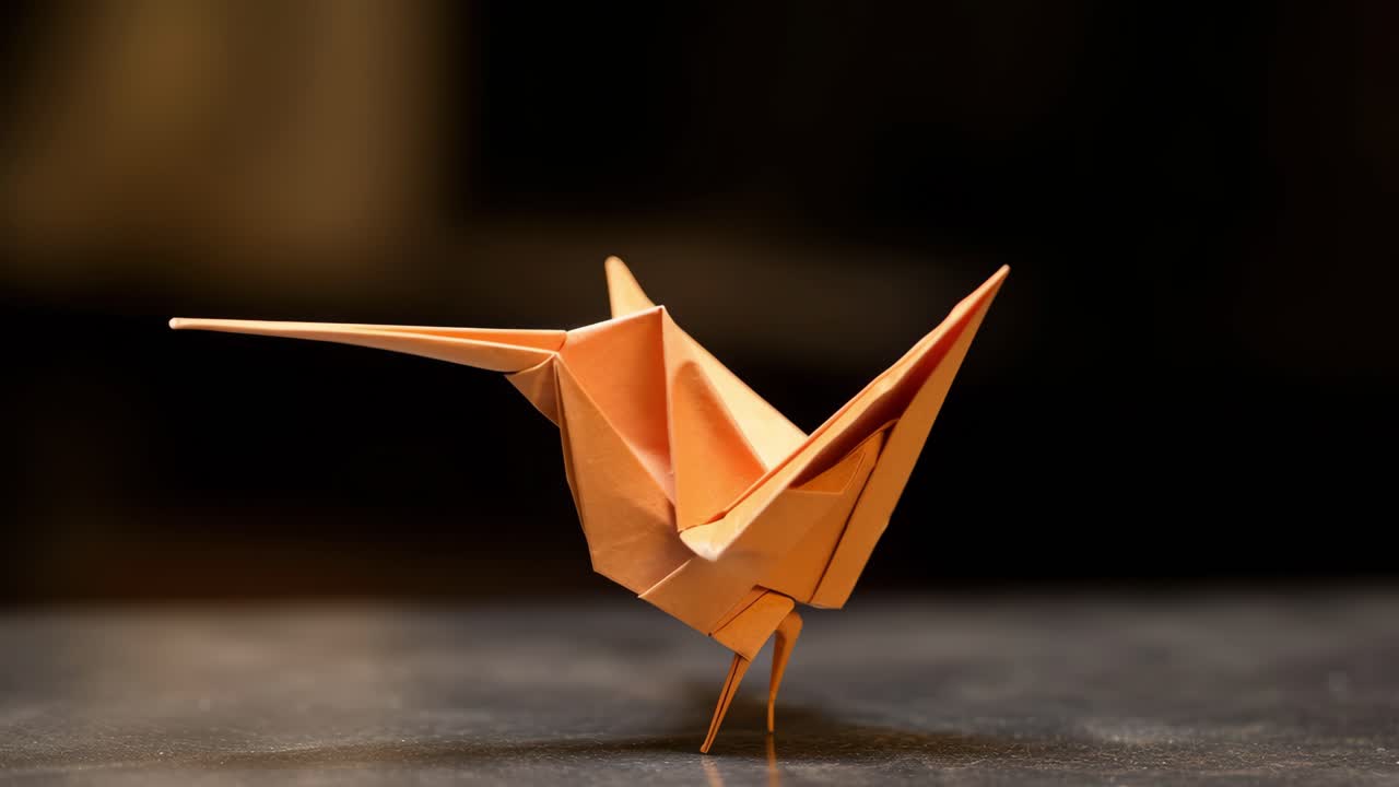 Displaying an origami hummingbird perched on a dark surface, showcasing its delicate, intricately folded wings against a softly blurred background, evoking a sense of tranquility and beauty