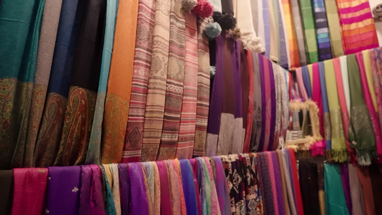 An array of colorful Moroccan scarves and fabrics displayed neatly inside a market stall