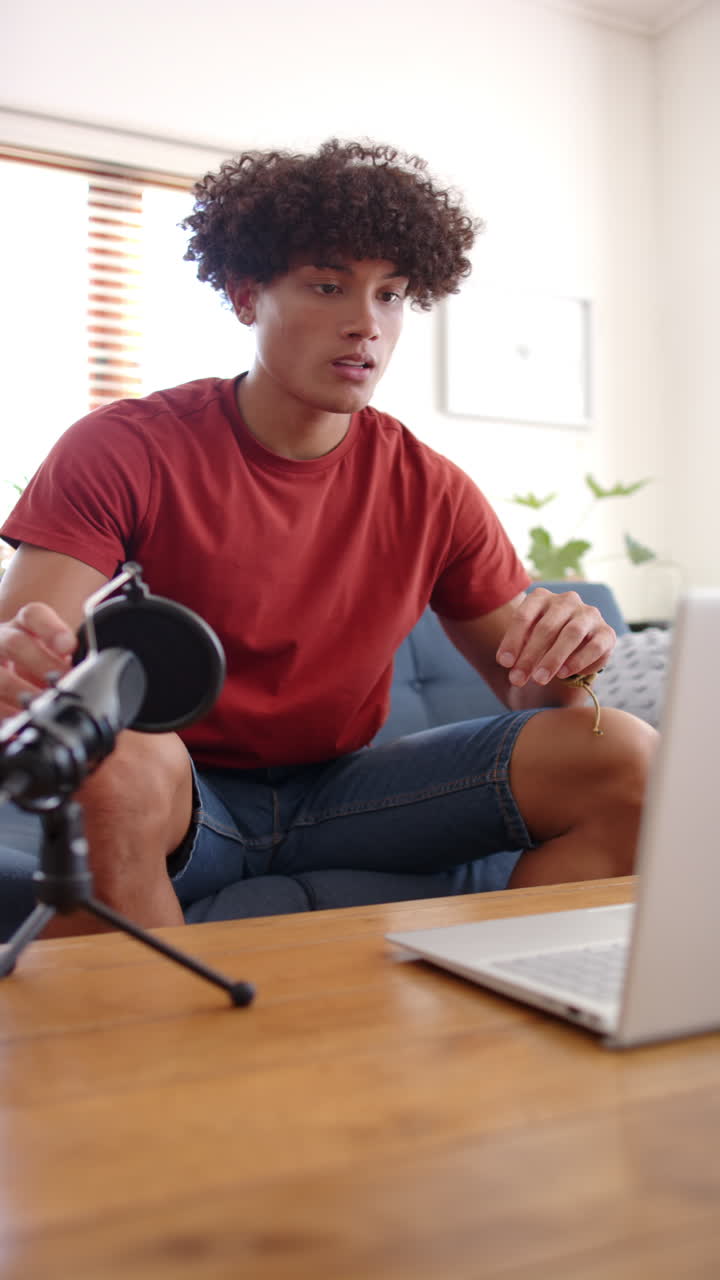 Vertical video: Recording podcast at home, man using laptop and microphone, focused on conversation