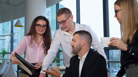 productive communication of coworkers at office. people discuss something depicted on the papers in woman's hands.