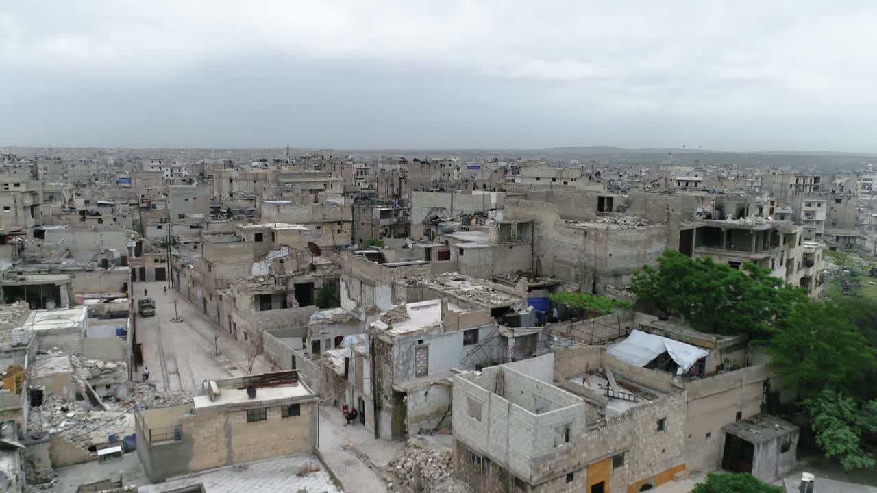 Drone che sorvola le case ad Aleppo sotto un cielo nuvoloso. Si possono vedere gli edifici e le case della città siriana in rovina dopo la guerra 4K