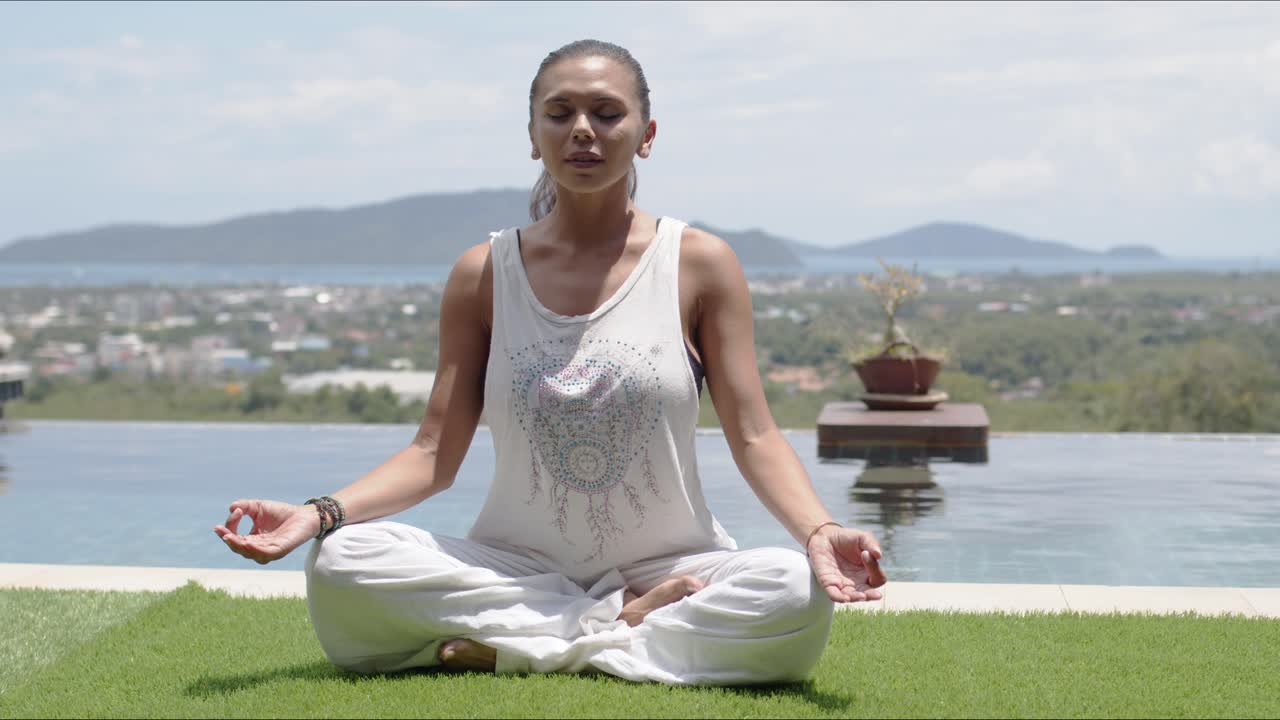 una mujer practicando yoga en la postura del loto contra la costa del océano.