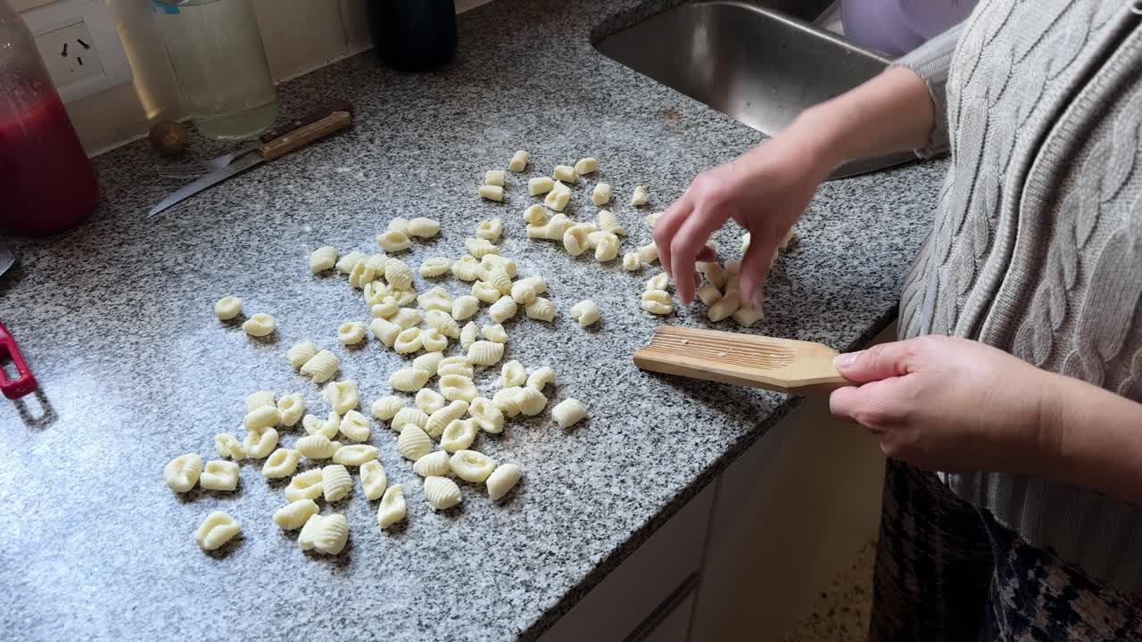 Donna che forma gli gnocchi con una cavarola - asse per gnocchi. - Primo piano