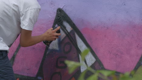 unrecognizable man doing spray paint graffiti on a wall in slow motion. vandalism.