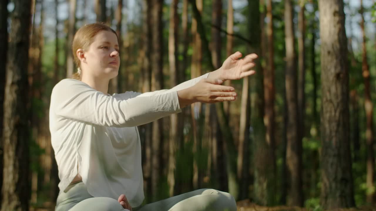 Женщина практикует йогу в лесу.