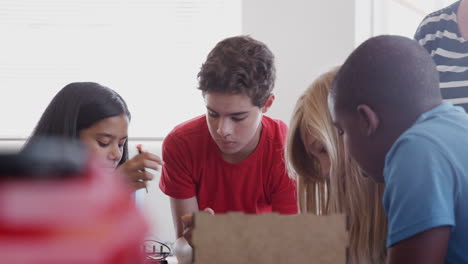 students with female teacher in after school computer coding class learning to program robot vehicle