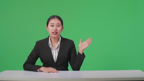 live news studio with professional asian female anchor pointing on something while reporting on the events of the day on the green screen