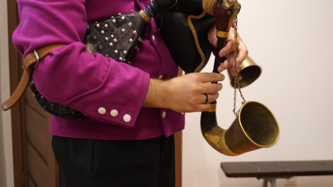 hombre con chaqueta púrpura folk toca un instrumento folk gaita de fondo suave