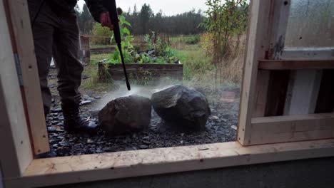 a man is employing a pressure hose to cleanse the rocks intended for the construction of a greenhouse in indre fosen, norway - close up