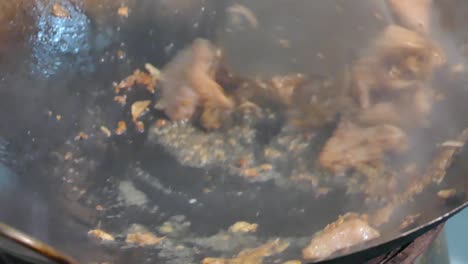 cooking stir fried garlic and pepper pork in wok with smoke of aroma float on it, close up, slow-motion