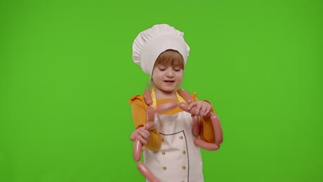 Teen-child-girl-dressed-as-cook-chef-in-apron-dancing-with-sausages,-fooling-around-on-chroma-key