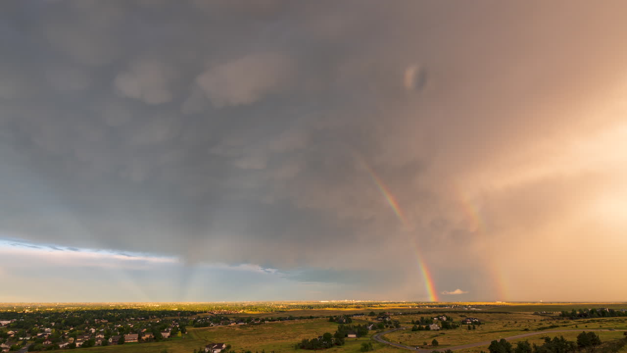 un hermoso arco iris se extiende desde una tormenta eléctrica que viene de las montañas en fort collins, colorado.