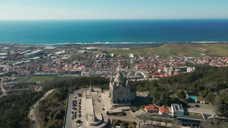 Aerial:-Santa-Luzia's-embrace-over-Viana,-where-land-meets-azure-sea