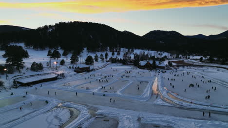 Evergreen-Lake-House,-Januar,-Mittwinter,-Eislaufen,-Teichhockey-Und-Eisfischen-Unter-Lichtern,-Sonnenuntergang,-Colorado,-Filmische-Vorwärtsbewegung