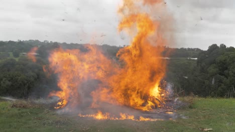 Eine-Zeitlupenaufnahme-Eines-Großen-Lagerfeuers-Auf-Einem-Ländlichen-Grundstück,-Bei-Dem-überall-Asche-Fliegt