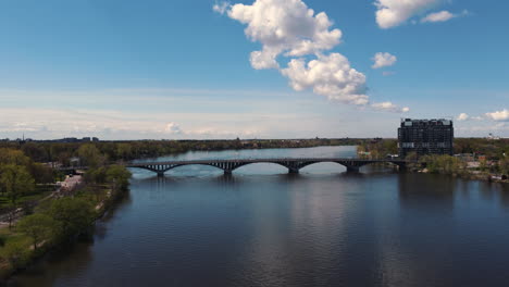 Luftaufnahme,-Drohnenansicht,-Annäherung-An-Eine-Brücke-über-Den-Fluss,-Vorbeifahrende-Autos,-Skyline,-Stadtbild,-Vorortstraßenansicht,-Himmel,-Skyline,-Landschaft,-Szene,-Szenisch,-Natur