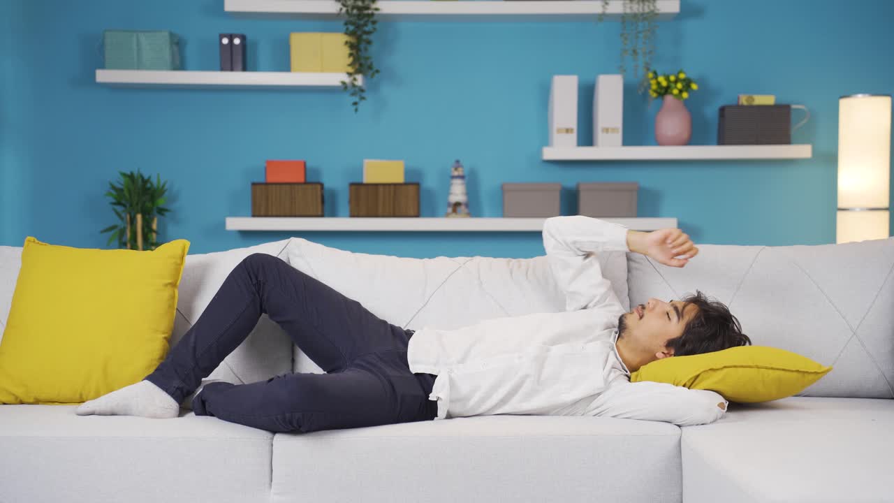 소파에 누워 있는 남자가 휴식을 취하고 있습니다.