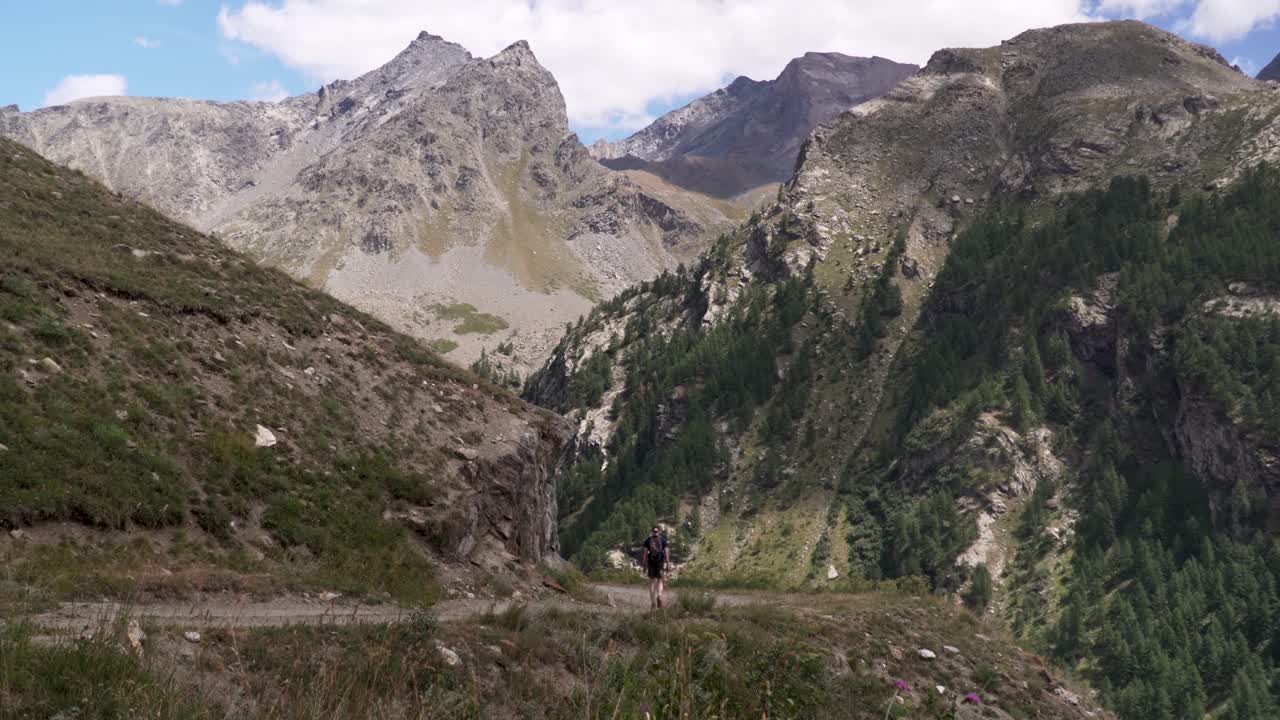 joven excursionista caminando por un camino de grava en un pintoresco valle en los hermosos alpes suizos
