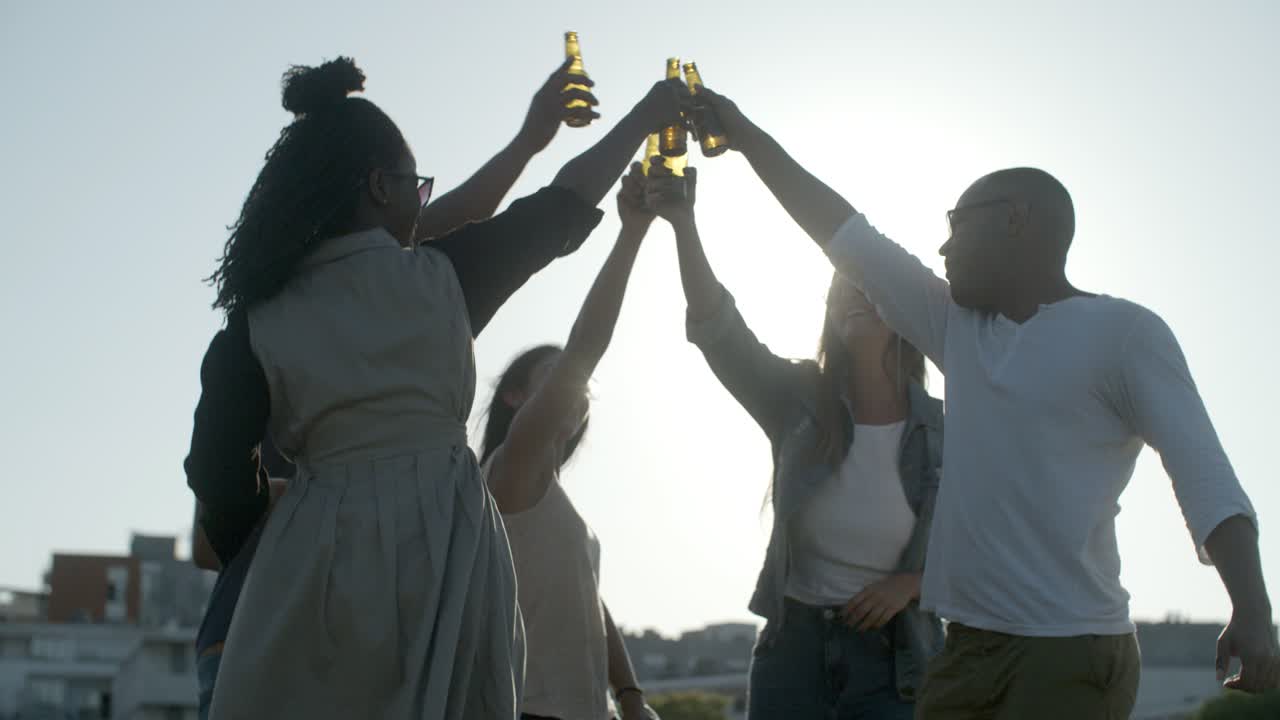 personas felices haciendo sonar botellas de cerveza mientras bailan