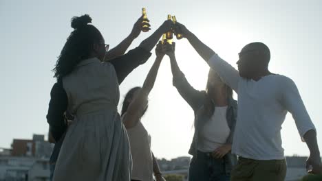 happy people clinking beer bottles while dancing