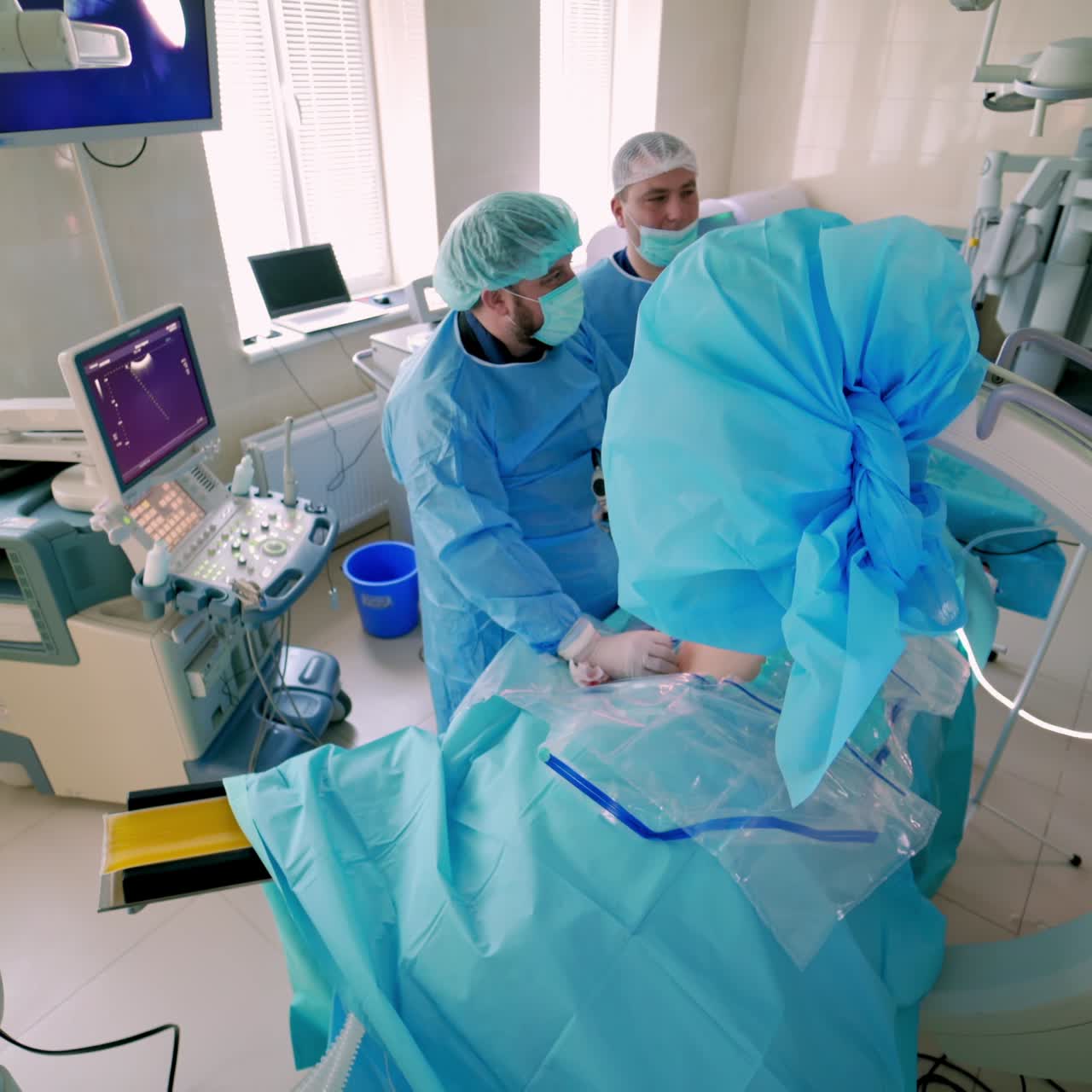 Medical specialists in modern operating room. Doctors perform a surgery and looking on the process on the monitor. Video from the top