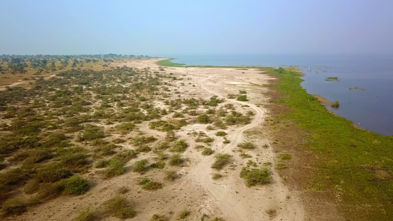 Droneopptak som fanger den uberørte strandlinjen til Lake Albert i Uganda, og viser den naturlige skjønnheten til denne afrikanske store innsjøen med sitt særegne landskap og rolige vann.