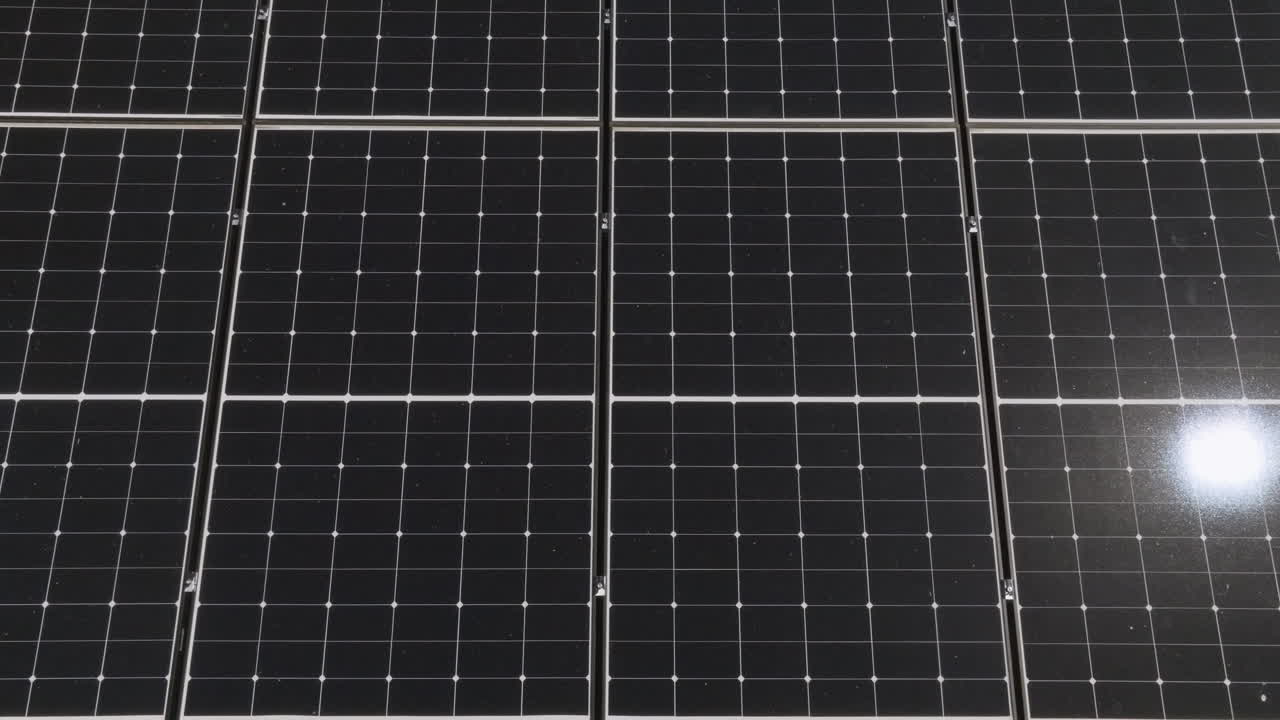 Aerial view above reflecting photovoltaic solar panels on a house roof, sunny day