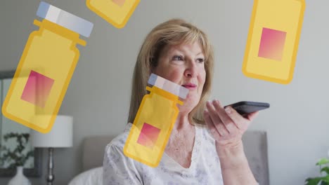 Animation-of-box-with-pills-icons-over-happy-senior-caucasian-woman-talking-on-smartphone