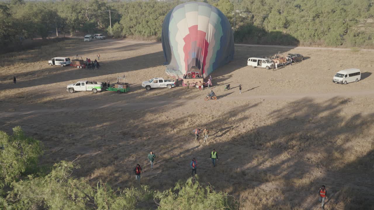 Hot Air Balloon Inflation in Open Field with People and Vehicles