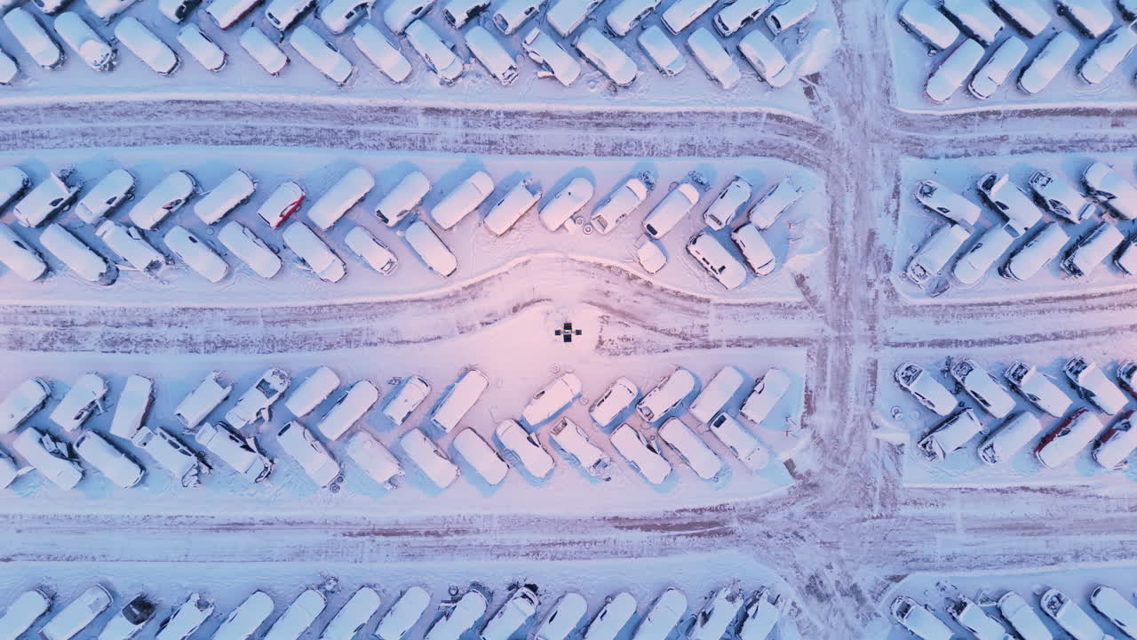 Neatly arranged car scrap yard covered in snow, abstract top down aerial riser