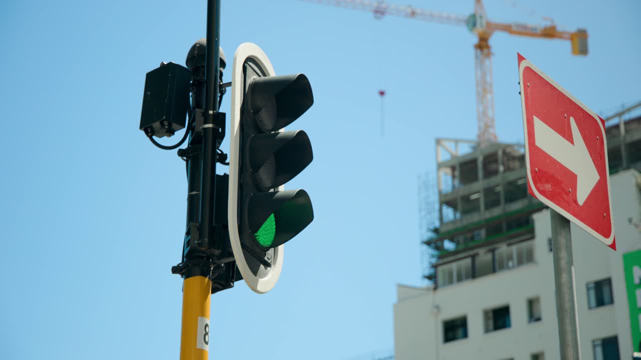 Semáforo mudando de vermelho para verde, permitindo a passagem de pedestres em um cruzamento com um guindaste, e espaço para texto.