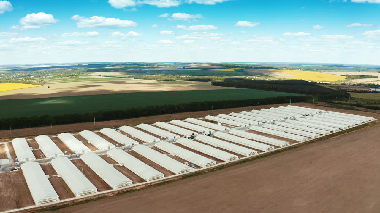 Industrial factory in rural place. Long white buildings of innovative plant on the natural background of fields. Aerial view.