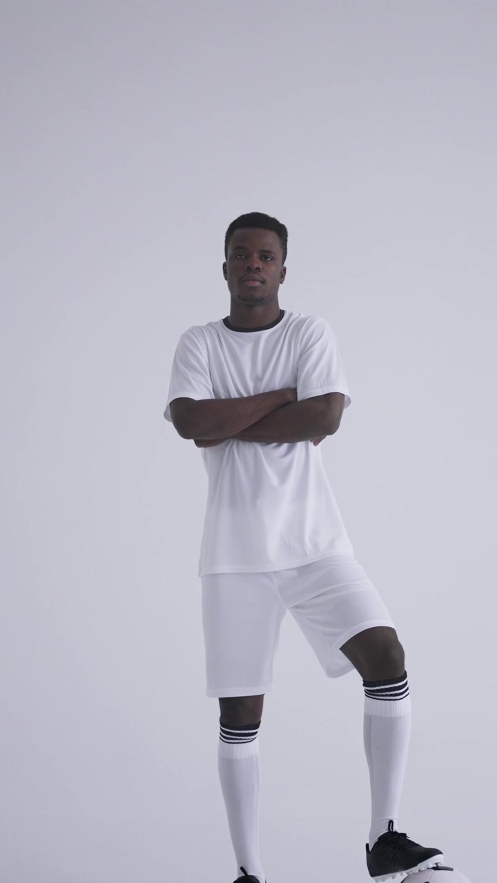 Calciatore afroamericano sicuro di sé in posa con il pallone.