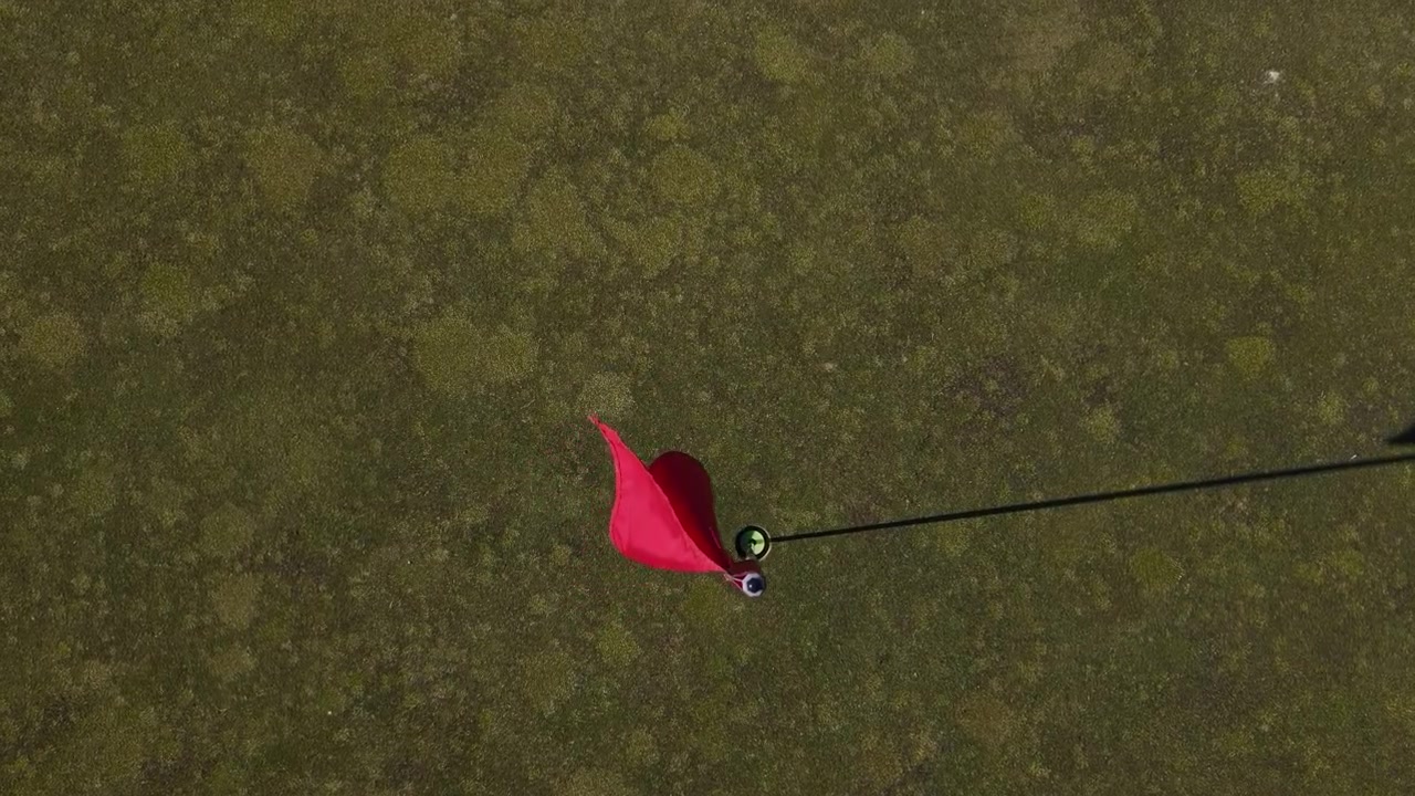Top view of red golf pole flag on manicured green at golf course in Australia